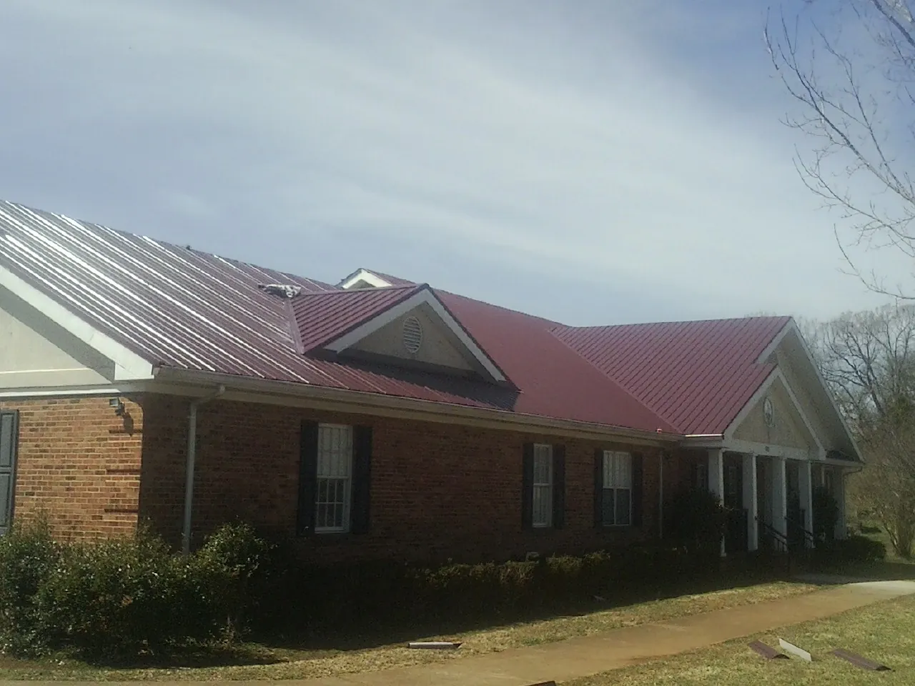 Red metal roof with gabled entries on a long brick building in Newark