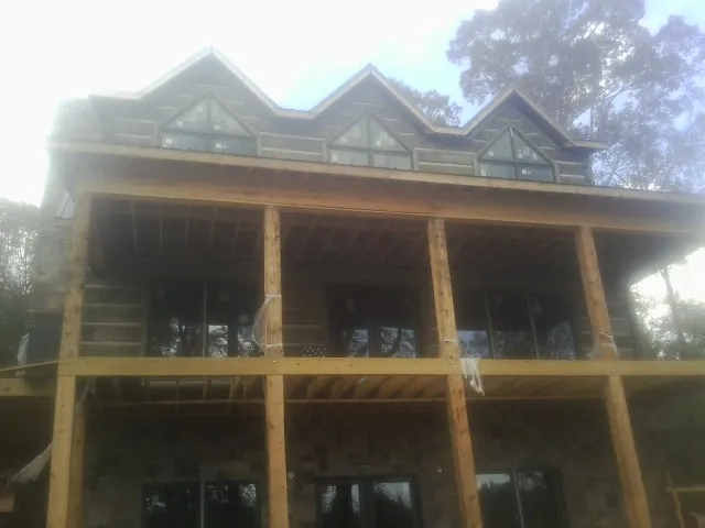 Dormers and porch framing on a large log home under construction — Roof Coating work by our crew in Newark